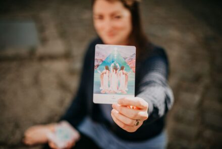 Beitragsbild zum Blog-Beitrag "Von der Selbstständigkeit in die Festanstellung" von Suzanne Frankenfeld. Auf dem Bild zu sehen ist Suzanne auf dem Boden sitzend (verschwommen), wie sie in eine Orakelkarte (scharfgestellt) in die Kamera hält. Auf der Orakelkarte steht "Yes".