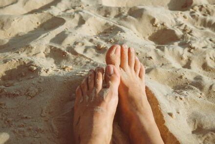Nackte Füße im Sand, im Sonnenschein.