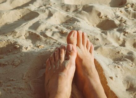 Nackte Füße im Sand, im Sonnenschein.