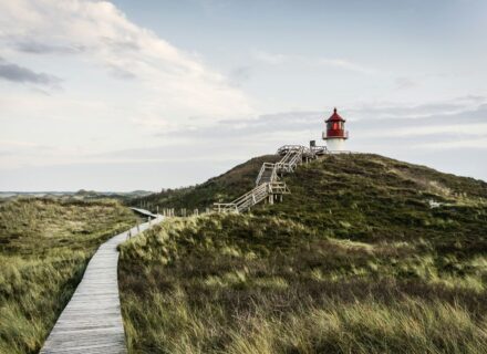 Ein Bohlenweg führt durch Dünen zu einem Seezeichen hin. Aufgenommen auf Amrum.